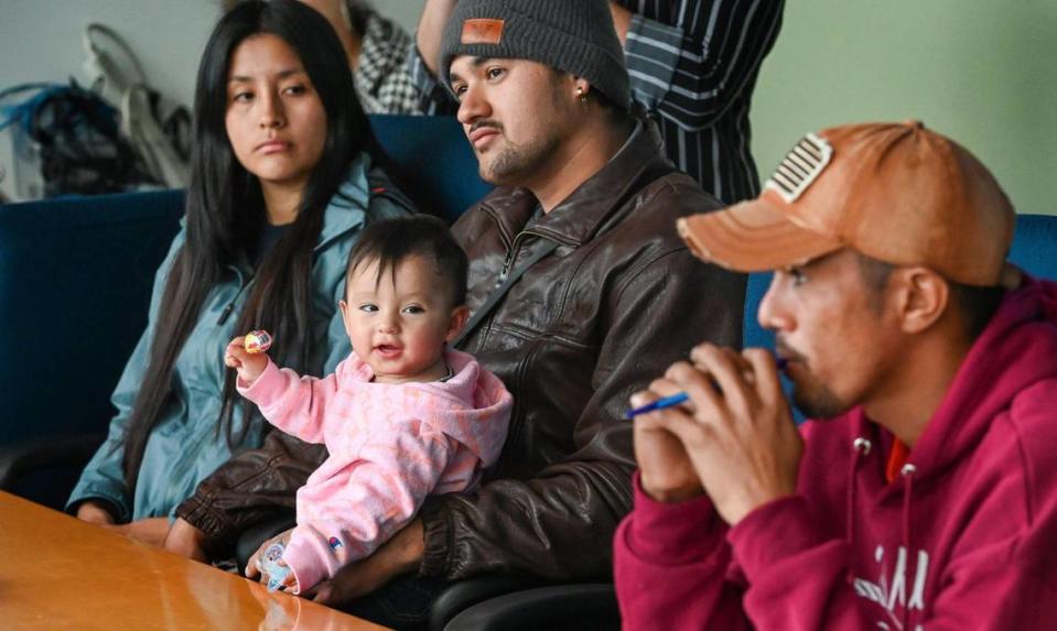 Venezuelan asylum seeker Jose Morales, center, sits with his wife, Katherine Rosas, left, and their 10-month-old daughter Danna Morales Rosas, and other immigrants while meeting with city officials and social workers on Friday, Feb. 2, 2024. The family arrived by bus in Fresno from Texas, by way of Denver, as part of a group of 16-20 others the previous weekend.