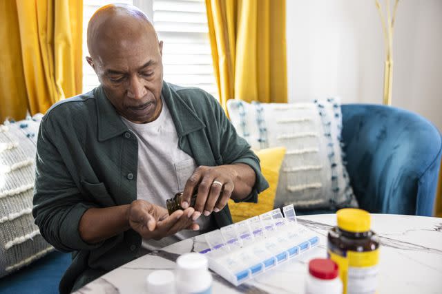 <p>MoMo Productions / Getty Images</p> Older male sorting prescription medications at kitchen table