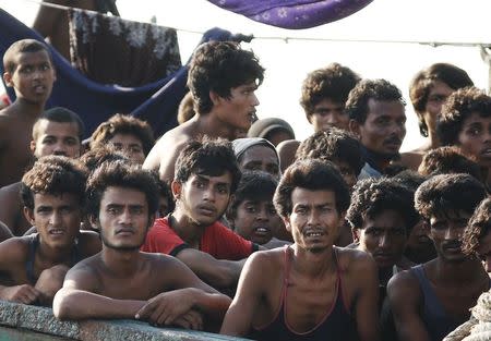 Migrants are seen aboard a boat tethered to a Thai navy vessel, in waters near Koh Lipe island, May 16, 2015. REUTERS/Olivia Harris