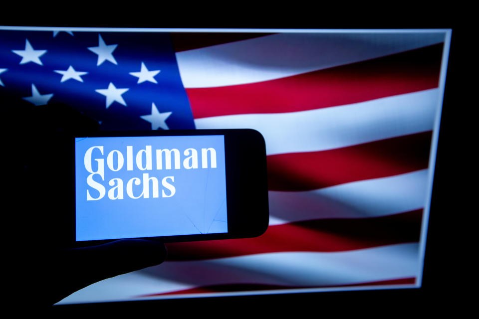 The logo of the Investment Bank Goldman Sachs is seen on a screen in front of an American flag. It is listed in the Dow Jones as it is one of the major US companies on the stock market. (Photo by Alexander Pohl/NurPhoto via Getty Images)