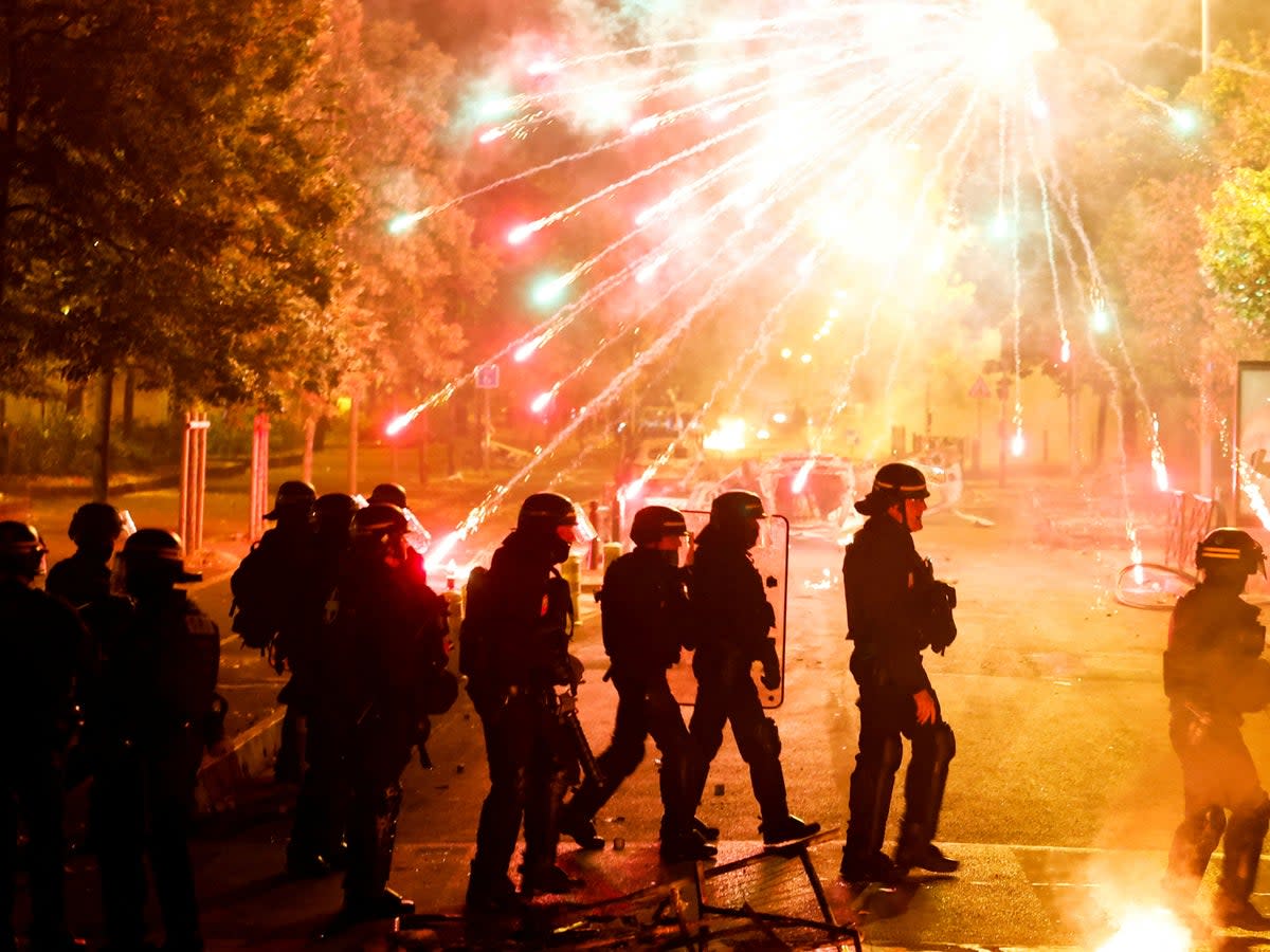French police stand in position as fireworks go off during clashes with protesters in Nanterre (Reuters)