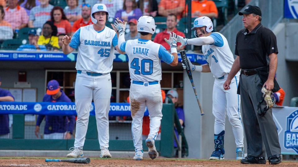 Angel Zarate scores and is greeted by North Carolina teammates Hunter Stokely, left, and Danny Serretti, right, during the Tar Heels’ defeat of Clemson in the ACC baseball tournament on Tuesday night in Charlotte.