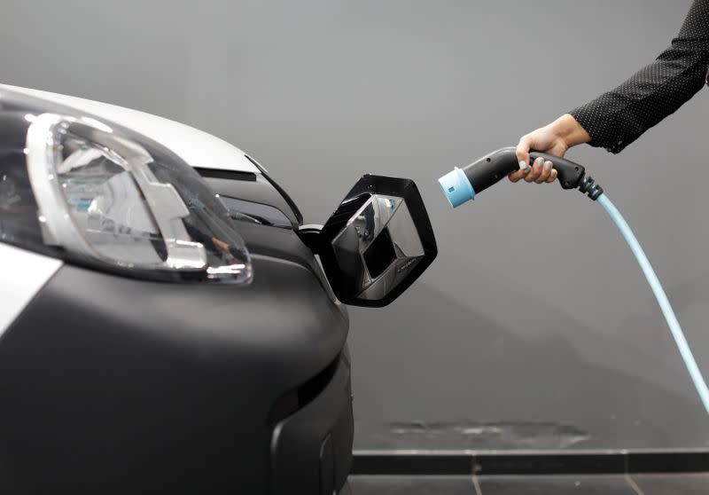 A woman holds a cable to charge up a Renault Kangoo ZE electric utility vehicle at a Renault automobile dealership in Cagnes-Sur-Mer