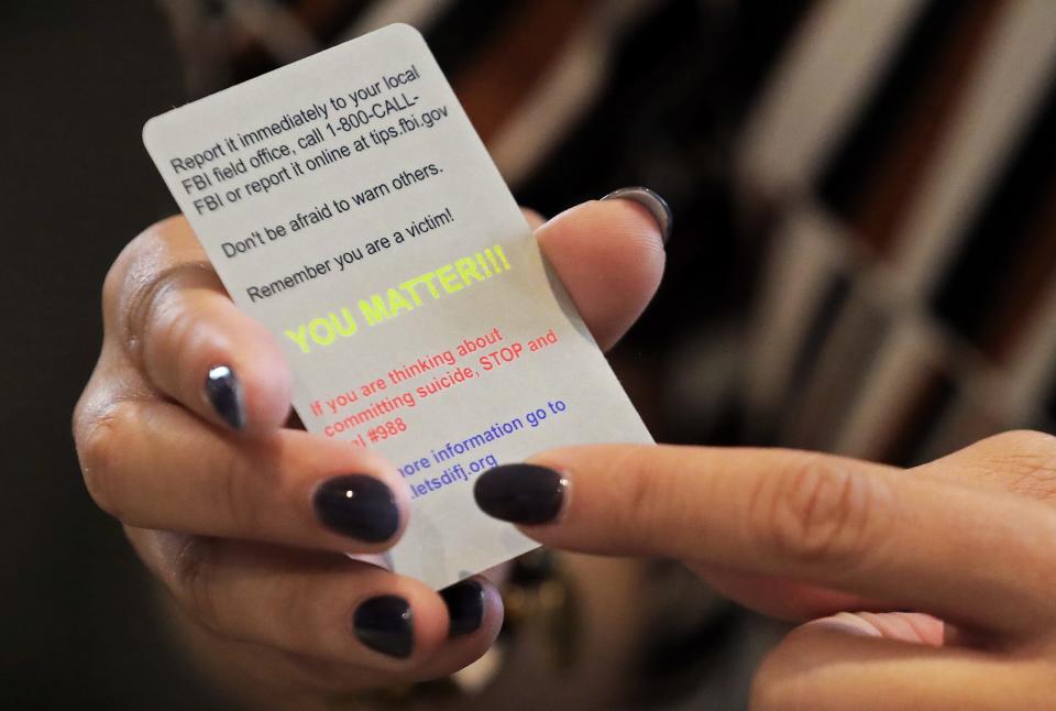 Tamia Woods shows one of the tips cards she and her husband had made to give to young people to let them know where to turn if they become victims of sextortion.