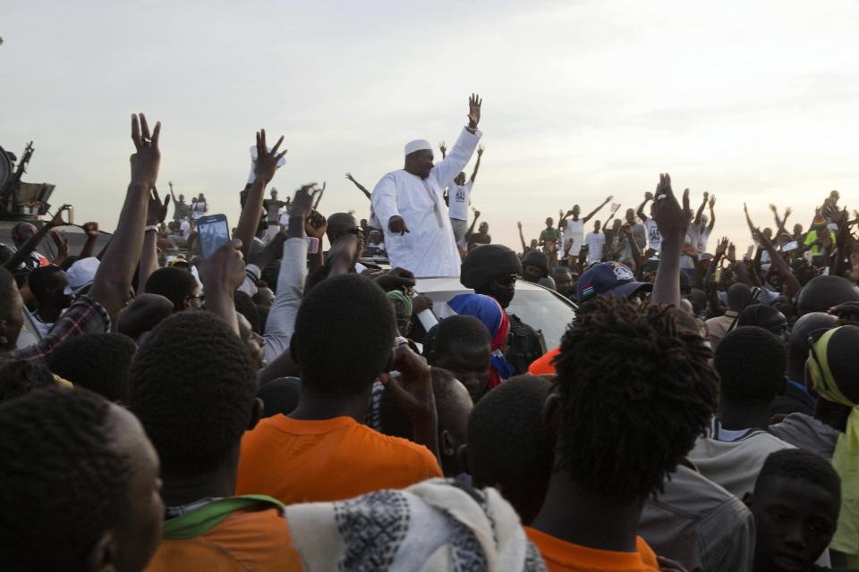 Gambian President Adama Barrow, centre, waves as he rides his motorcade through crowds of hundreds of thousands after arriving at Banjul airport in Gambia, Thursday Jan. 26, 2017, after flying in from Dakar, Senegal. Gambia's new president has finally arrived in the country, a week after taking the oath of office abroad amid a whirlwind political crisis. Here's a look at the tumble of events that led to Adama Barrow's return — and the exile of the country's longtime leader. (AP Photo/Jerome Delay)