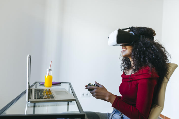 Woman playing with virtual reality glasses and laptop