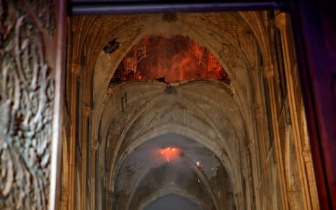 Flames and smoke are seen as the interior continues to burn inside the Notre Dame Cathedral  - Credit: Reuters