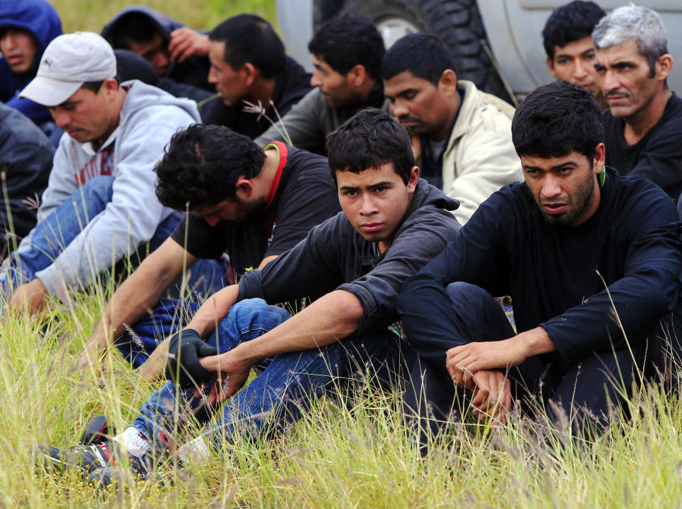 Immigrants suspected of being in the country illegally sit in a group after U.S. Border Patrol agents detained about 75 immigrants who'd been living in hut for several days in a brushy area Thursday April 17, 2014 near North 10 St. and Sprague St. in McAllen, Texas. Agents spent about three hours rounding up the immigrants suspected of being in the country illegally after they responded to the area. Most of the immigrants are believed to be from Central America. (AP Photo/The Monitor, Gabe Hernandez))