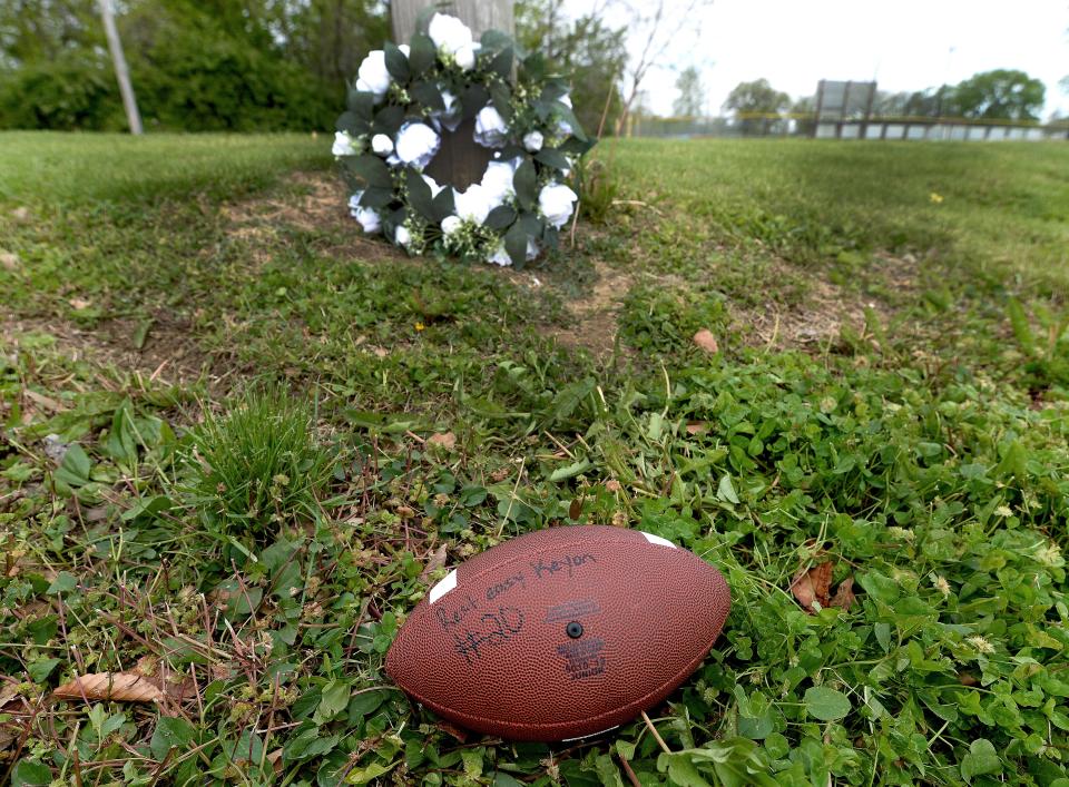 A football with the words "Rest easy Keyon #20" and a bouquet sprung up at Dreamland Park on April 24, 2024. Keyon Day, a Southeast High School student, was identified as a shooting victim in the area of the park on Wednesday.