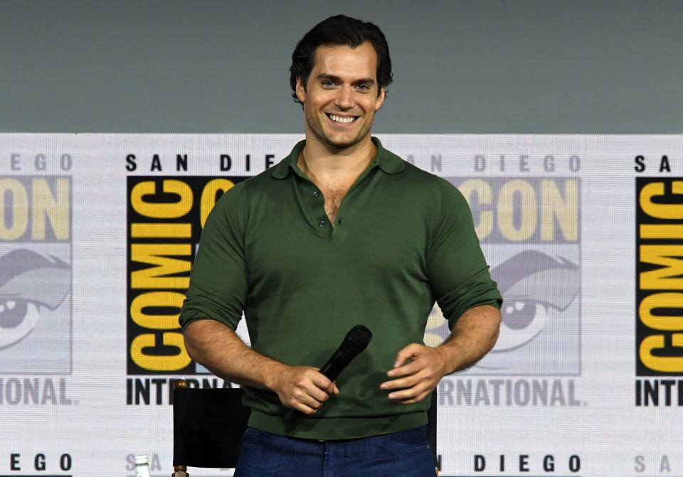 Henry Cavill has a coy smile on his face as he holds the mile to address a crowd. 