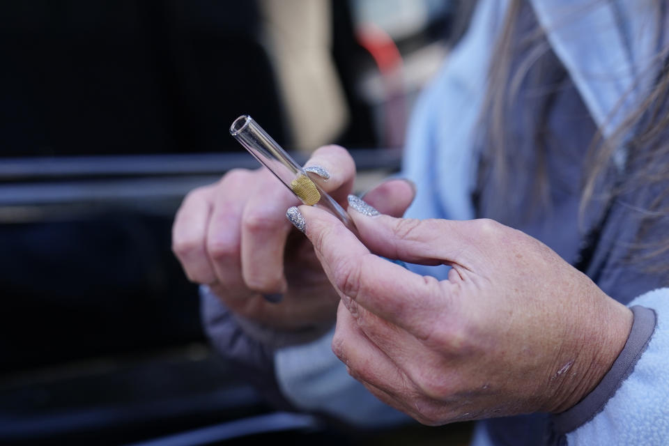 Jessie Blanchard, center, shows a participant how to use a straight pipe as she hands out other goods like food, Naloxone, needles, tourniquets, and condoms to members of the community on Monday, Jan. 23, 2023, in Albany, Ga. (AP Photo/Brynn Anderson)