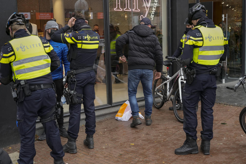 Police check ID's as they patrol the city center after a demonstration against COVID-19 restrictions and lockdown was banned in Nijmegen, eastern Netherlands, Sunday, Nov. 28, 2021. (AP Photo/Peter Dejong)