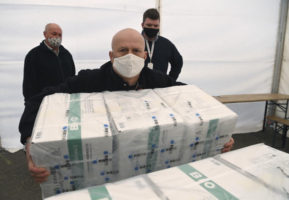 An employee unloads the newly arrived coronavirus vaccines from Chinese pharmaceutical company Sinopharm at the logistics base set up to in the parking lot of the government office in the 13th district of Budapest, Hungary, Monday, March 29, 2021. (Noemi Bruzak/MTI via AP)