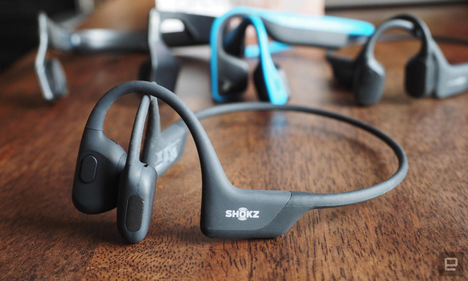 Shokz OpenRun Pro bone conduction headphones in grey shown close-up on a wooden table top.