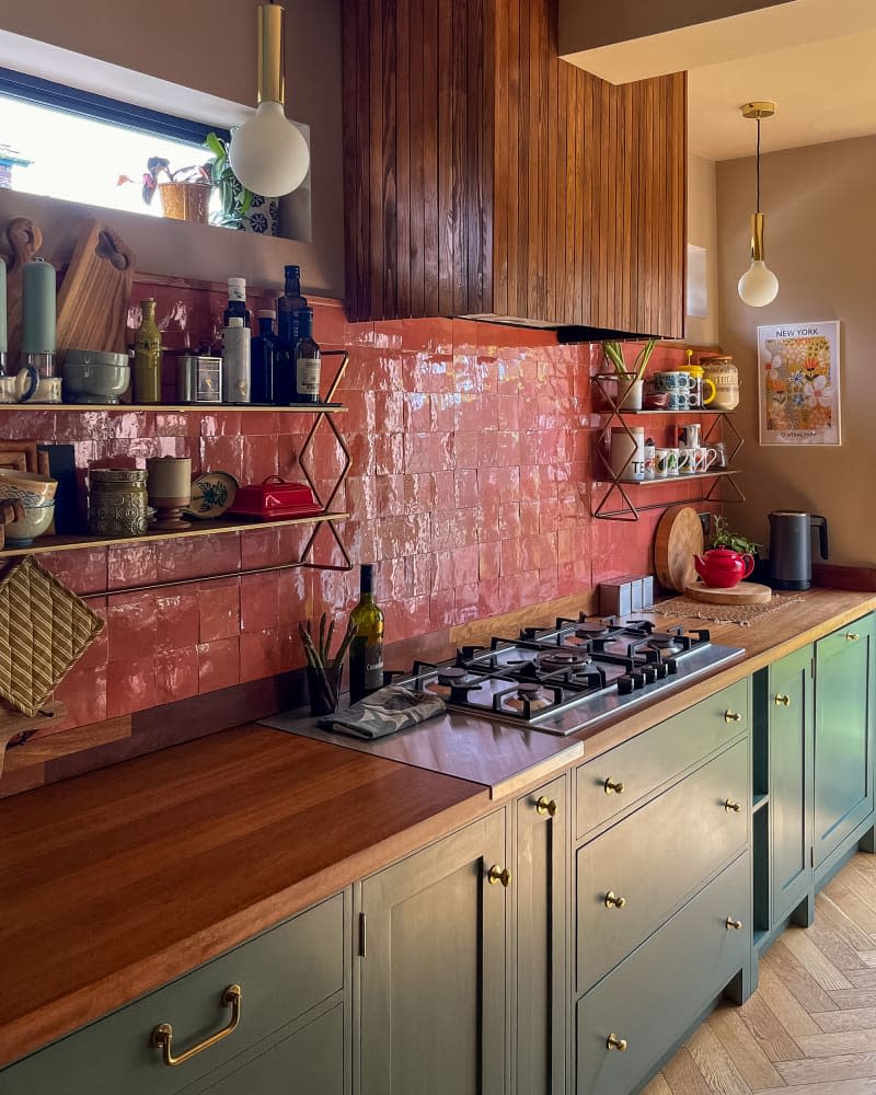 Green cabinets in kitchen with pink tile backsplash.