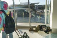 A person sleeps on the floor as passengers travel Wednesday, Nov. 22, 2023, at Los Angeles International Airport in Los Angeles. The late crush of holiday travelers is picking up steam, with about 2.7 million people expected to board flights on Wednesday and millions more planning to drive or take the train to Thanksgiving celebrations. (AP Photo/Damian Dovarganes)