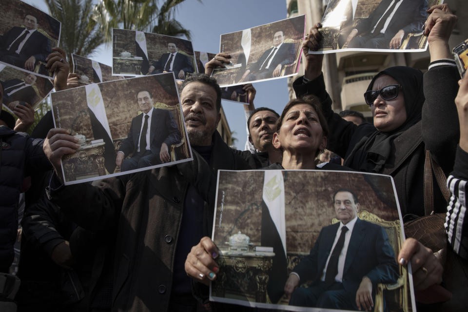 Supporters of ousted President Hosni Mubarak hold posters with his photograph near the cemetery where he will be buried, in the Heliopolis neighborhood of Cairo, Egypt, Wednesday, Feb. 26, 2020. Egypt is holding a full-honors military funeral for Mubarak who was ousted from power in the 2011 Arab Spring uprising. Mubarak, 91, died Tuesday at a Cairo military hospital from heart and kidney complications. (AP Photo/Nariman El-Mofty)