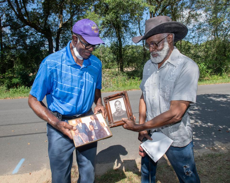Charles Smith, right, hands a photo of Roebuck Rich to his cousin Gus Rich, who is holding a photo of their uncles, as they talk about their family's history along Persimmon Hollow Road in Milton on Friday, Aug. 18, 2023.