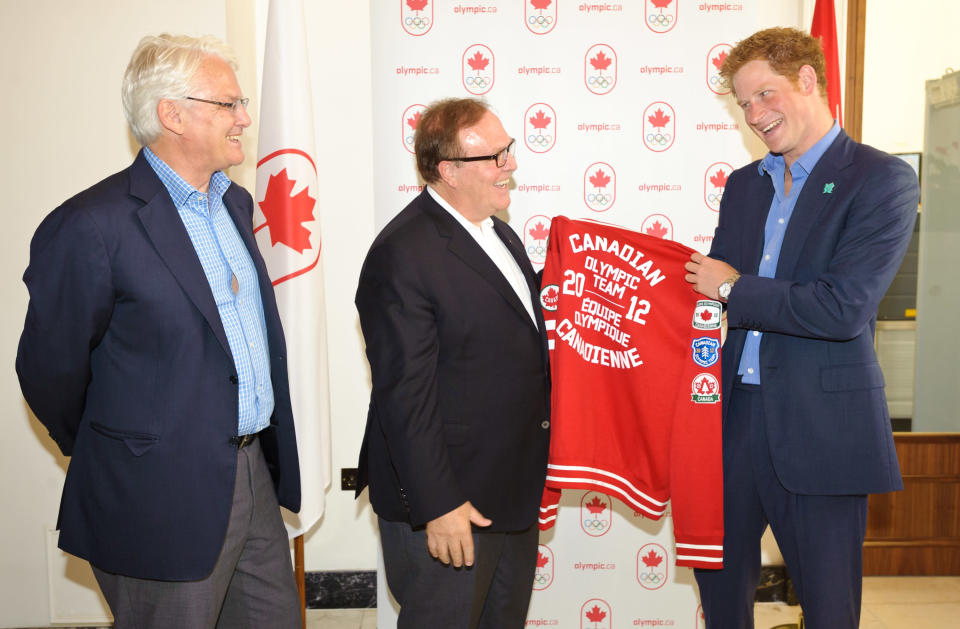 Prince Harry is presented an official 2012 Canadian Olympic Team jacket by Canadian Olympic Committee President Marcel Aubut (centre) while Canada’s High Commissioner to the United Kingdom, Gordon Campbell looks on at Canada Olympic House, London, Thursday Aug. 2, 2012. (Canadian Olympic Committee Photo)