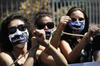 Lebanese anti-government activists handcuff their hands by rope with Arabic stickers on their mouths that read:"We will continue," as they protest outside a Lebanese court demanding the improving judicial independence, in Beirut, Lebanon, Wednesday, June 17, 2020. A year after anti-government protests roiled Lebanon, dozens of protesters are being tried before military courts that human rights lawyers say grossly violate due process and fail to investigate allegations of torture and abuse. (AP Photo/Hussein Malla)