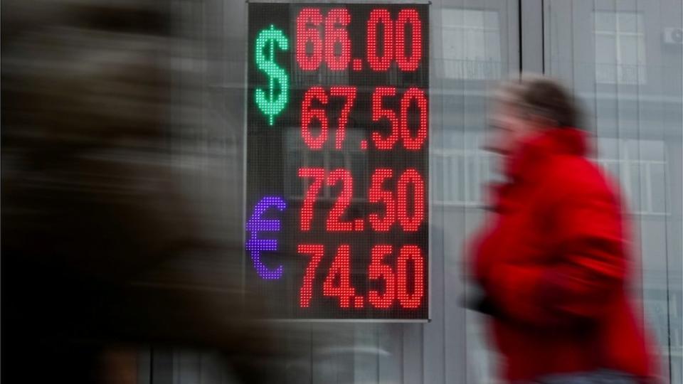 Mujer junto a un panel con la cotización del euro y el dólar.