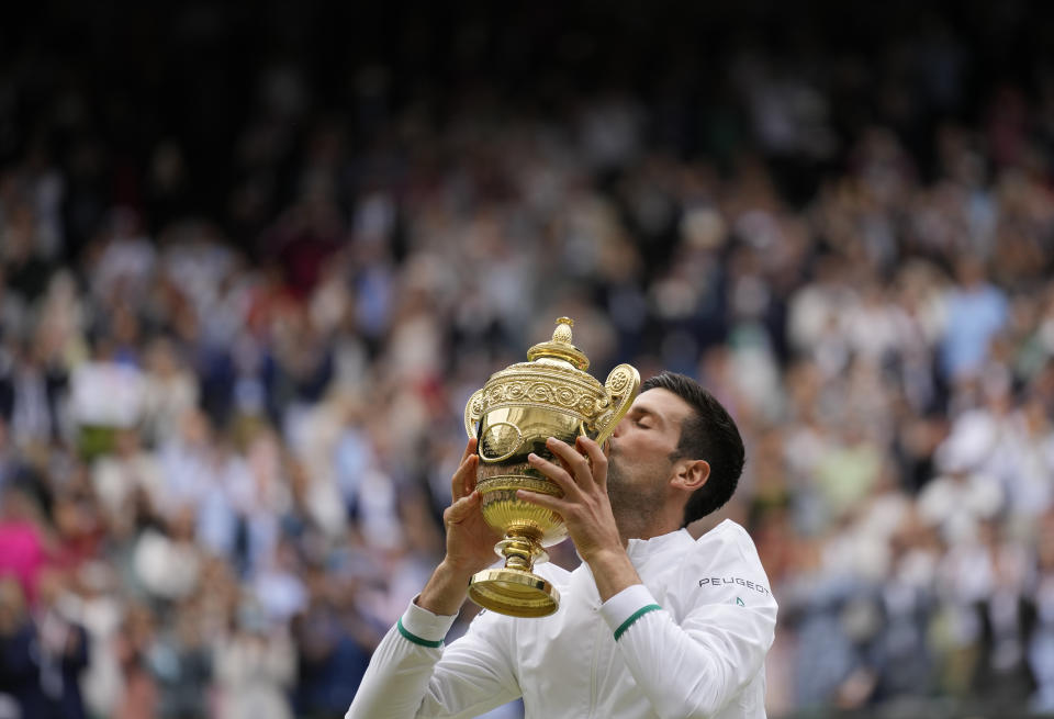 Serbia's Novak Djokovic kisses the winners trophy as he poses for photographers after he defeated Italy's Matteo Berrettini in the men's singles final on day thirteen of the Wimbledon Tennis Championships in London, Sunday, July 11, 2021. (AP Photo/Kirsty Wigglesworth)