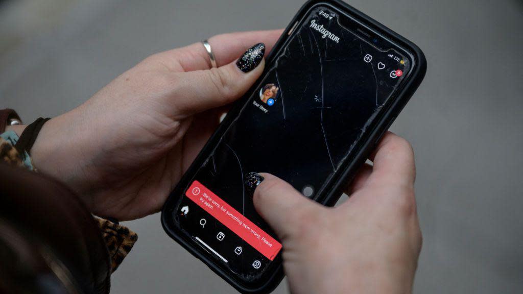 A woman checks her Instagram account on a street in New York city during Facebook's outage in October 2021