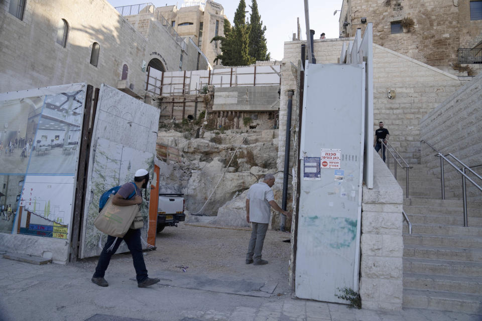 Hebrew University archaeologist Dr. Oren Gutfeld, center, opens a gate to the site of a Jewish ritual bath or mikveh, discovered near the Western Wall in the Old City of Jerusalem, Sunday, July 17, 2022. An excavation to build an accessible elevator from the Jewish Quarter to the Western Wall near the Temple Mount by the Hebrew University of Jerusalem's Institute of Archaeology has unearthed the mikveh that dates back to the 1st Century CE. (AP Photo/Maya Alleruzzo)