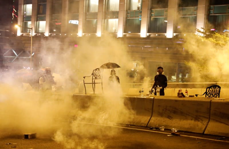 Anti-government demonstrators stand amid tear gas during clashes with police near the Hong Kong Polytechnic University (PolyU) in Hong Kong