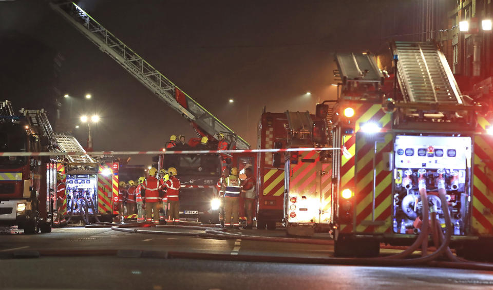 Fire fighters at the scene of a major fire at a student residential building in Bolton, England, late Friday Nov. 15, 2019.  Fire crews tackled the large blaze described by an eye witness as "crawling up the cladding" of a student accommodation building, with occupants still being accounted for Saturday morning. (Peter Byrne/PA via AP)