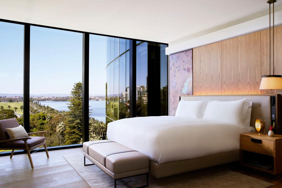 Hotel room with a bed and ceiling to floor windows overlooking a waterfront