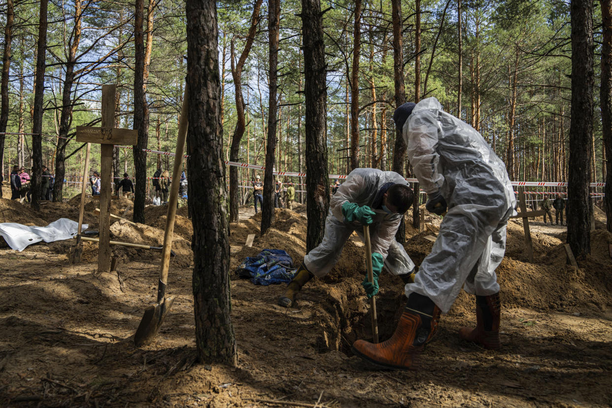 Emergency workers dig a grave of a civilian during an exhumation in the recently retaken area of Izium, Ukraine, Saturday, Sept. 17, 2022. Ukrainian authorities discovered a mass burial site near the recaptured city of Izium that contained hundreds of graves. It was not clear who was buried in many of the plots or how all of them died, though witnesses and a Ukrainian investigator said some were shot and others were killed by artillery fire, mines or airstrikes. (AP Photo/Evgeniy Maloletka)