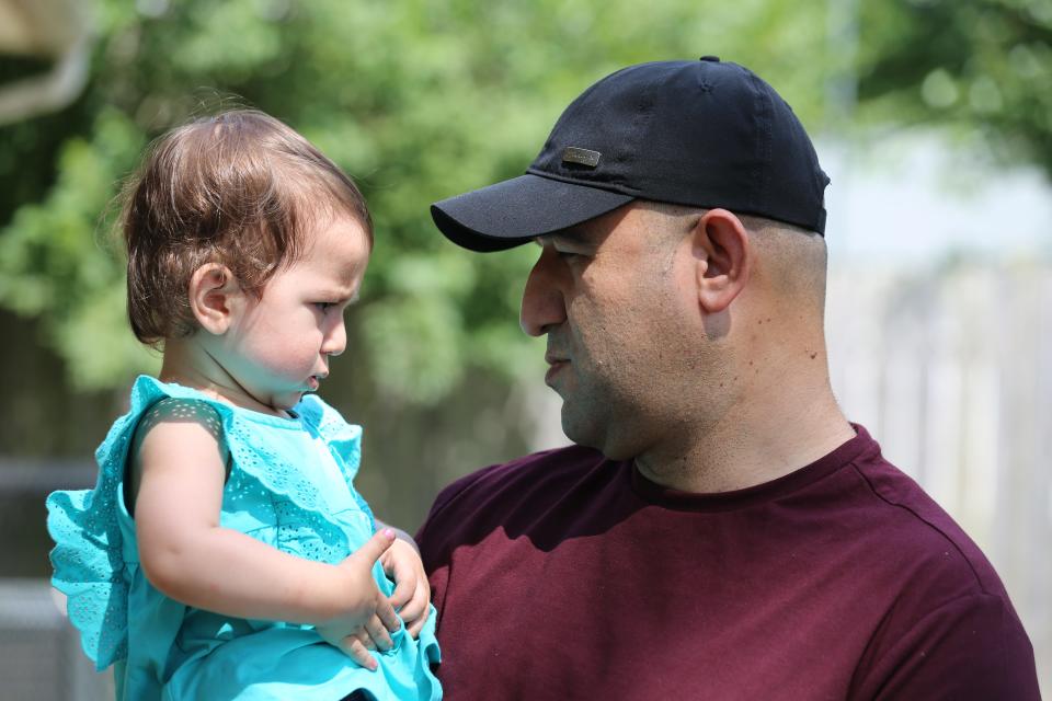 Tamim Bedar, who fled Afghanistan during the U.S. evacuation in 2021, holds his child outside his home in Louisville, Kentucky.