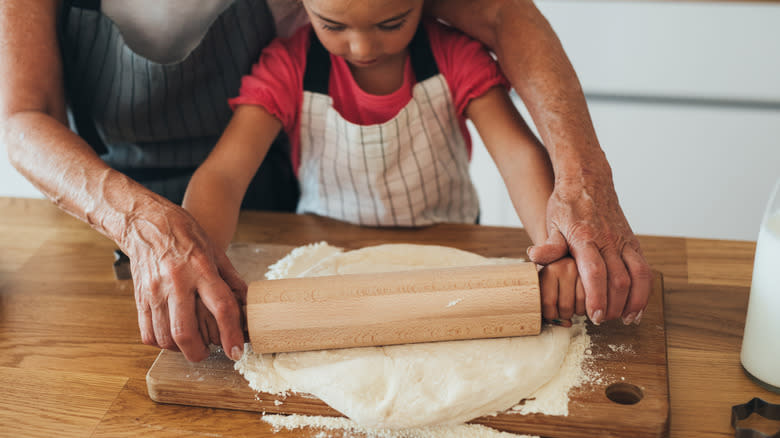 Family rolling dough in kitchen
