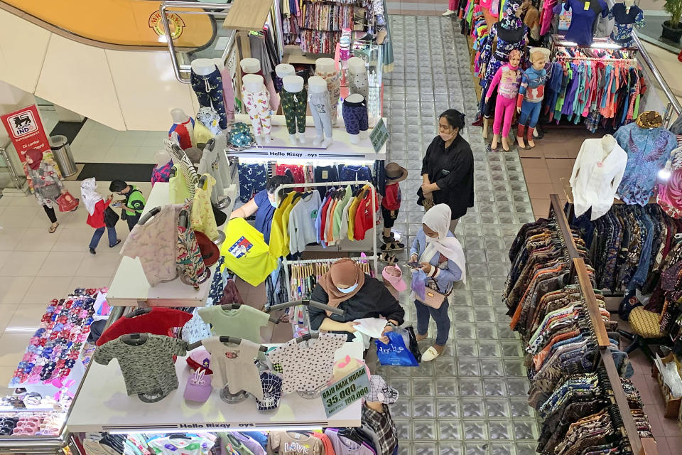 Women wearing face masks browse for clothings at a shopping mall in Jakarta, Indonesia, Friday, Dec. 30. 2022. Almost three years after officials announced the first confirmed case of COVID-19 in Indonesia, the country’s leader said Friday they are lifting all coronavirus-related restrictions nationwide. (AP Photo/Tatan Syuflana)