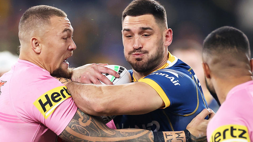 Ryan Matterson attempts to burst through two Penrith Panthers players during an NRL game.