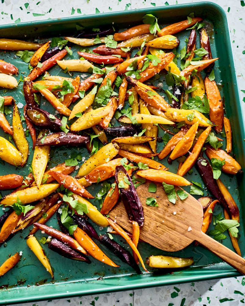 green baking sheet with various colors of roasted carrots and herbs