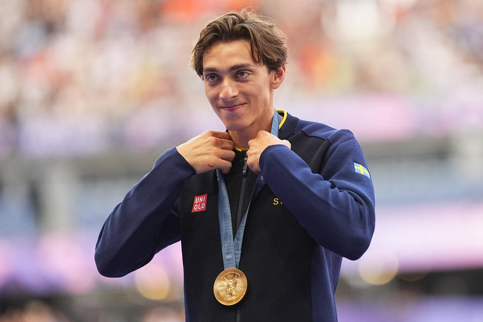 Pole vaulter Armand Duplantis hangs his gold medal around his neck.