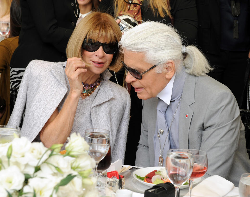 Anna Wintour whispering to Karl Lagerfeld at a table