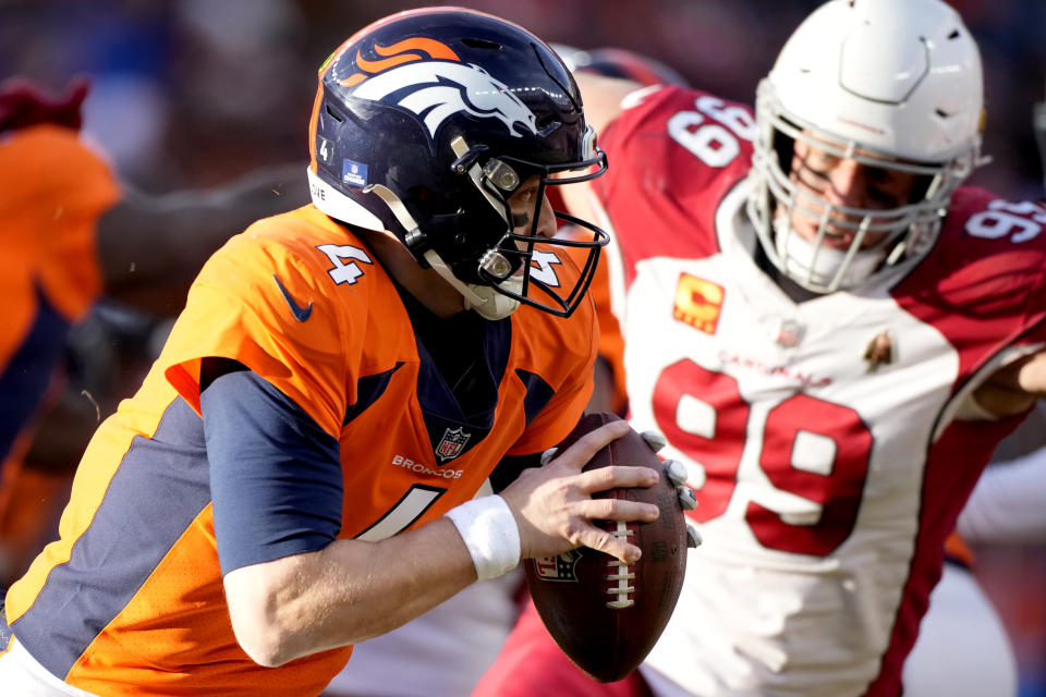 Denver Broncos quarterback Brett Rypien (4) runs as Arizona Cardinals defensive end J.J. Watt (99) pursues during the first half of an NFL football game, Sunday, Dec. 18, 2022, in Denver. (AP Photo/David Zalubowski)