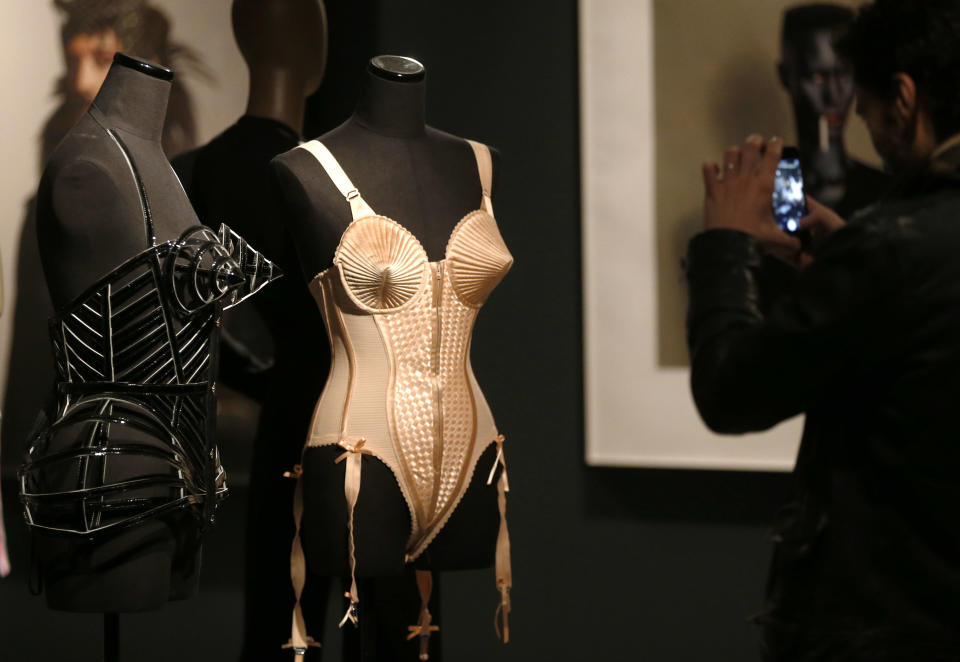 A visitor takes picture a creation of French couturier Jean Paul Gaultier during the launch of his exhibition 'The Fashion World of Jean Paul Gaultier : From the Sidewalk to the Catwalk' at the Barbican Art Gallery in London, Tuesday, April 8, 2014. (AP Photo/Sang Tan)