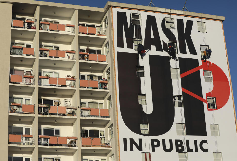 FILE - In this May 18, 2020, file photo a billboard is installed on an apartment building encouraging people to wear face masks in Cape Town, South Africa. For months, the city of Cape Town was the biggest coronavirus hot spot in Africa. Now, finally, there are signs of relief. (AP Photo/Nardus Engelbrecht, File)