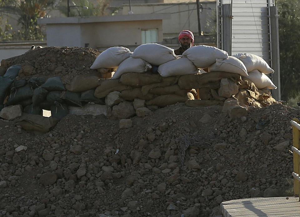 FILE - A militant with the Islamic State group peers from behind a barricade at a Kurdish peshmerga position near the Mullah Abdullah Bridge, located on the road between Irbil and Kirkuk, 290 kilometers (180 miles) north of Baghdad, Iraq, Sept. 27, 2014. Ten years after the Islamic State group declared its caliphate in large parts of Iraq and Syria, the extremists now control no land, have lost many prominent founding leaders and are mostly away from the world news headlines. (AP Photo/Hadi Mizban, File)