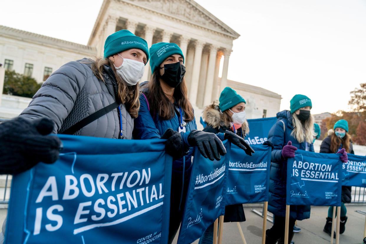 Abortion rights advocates hold signs that read "Abortion is Essential" as they demonstrate in front of the Supreme Court, Wednesday, Dec. 1, 2021, in Washington, D.C.