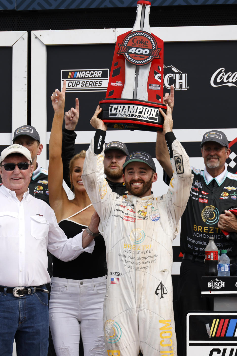 Austin Dillon lifts the championship trophy with his wife Whitney Dillon, second from left, and his grandfather and car owner Richard Childress, left, in Victory Lane after winning a NASCAR Cup Series auto race at Daytona International Speedway, Sunday, Aug. 28, 2022, in Daytona Beach, Fla. (AP Photo/Terry Renna)