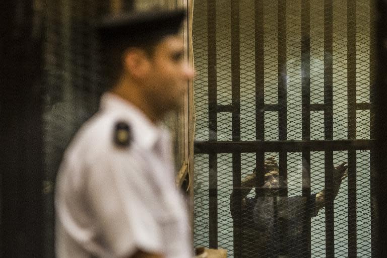 Ousted Egyptian president Mohamed Morsi (R), who was recently sentenced to death, gestures from inside the defendants' cage during his new trial in Cairo on May 23, 2015