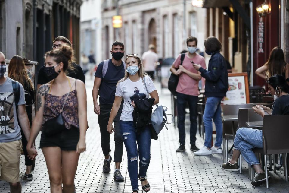 Young people wearing masks on a cobblestone street.