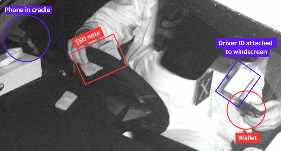 The same image of the driver as above but the phone is circled, where it sits in its cradle, and the $50 note in his hand and the wallet in the other are also highlighted.