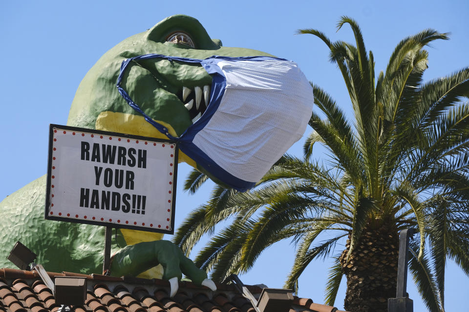 A giant dinosaur wearing a protective mask reminding people to wash their hands, is seen above the Ripley's Believe It or Not, in the Hollywood section of Los Angeles on Tuesday, April 21, 2020. (AP Photo/Richard Vogel)