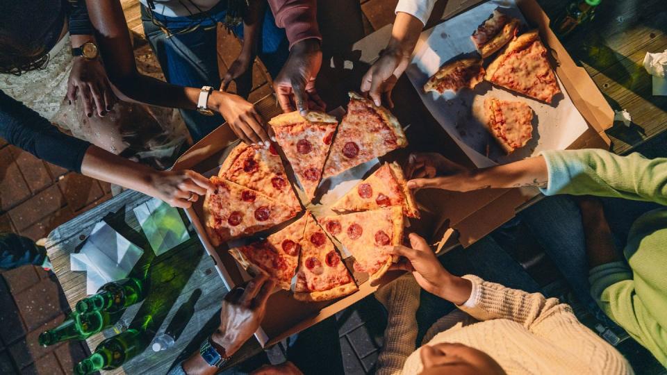 high angle view of people taking pizza slices